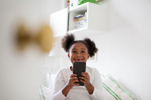 Girl playing with smartphone in her bedroom