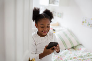 Girl playing with smartphone in her bedroom