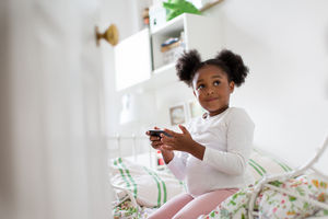 Girl playing with smartphone in her bedroom