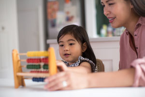 Girl using abacus to count with Mother