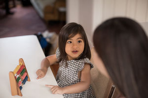 Girl using abacus to count with Mother