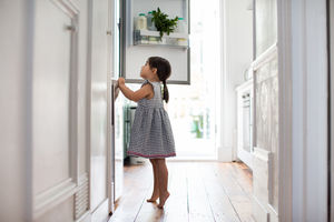 Girl standing on tip toes to look into refrigerator