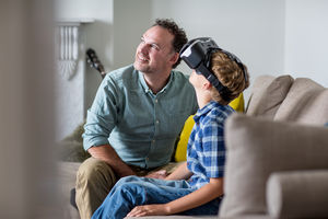 Boy using a VR headset game at home with Father