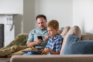 Father and Son individually using technology