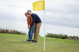 Father teaching son how to play golf