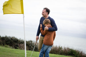 Father hugging son on golf course