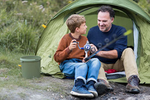 Father and Son looking at shells in rockpool on beach