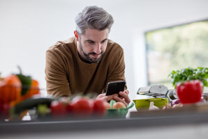 Adult male looking up recipe on smartphone in kitchen