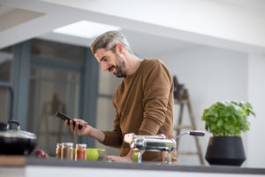 Adult male looking up recipe on smartphone in kitchen