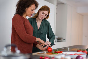 Friends looking at recipe on smartphone whilst cooking