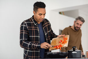 Adult male putting ingredients into a pan