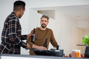 Male friends having a beer whilst cooking a meal