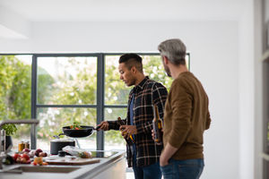 Male friends having a beer whilst cooking a meal
