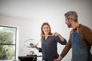 Couple tasting food whilst cooking
