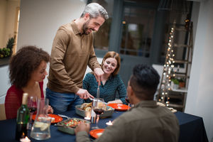 Adult male serving Christmas meal to friends