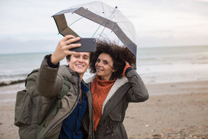 Young couple taking a selfie on a beach in bad weather