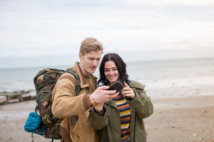 Young couple using smartphone on a winter break at beach