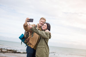 Young couple taking a selfie on the beach in winter