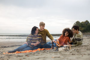 Group of young adult sitting around fire on winter break