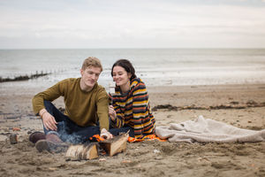 Young couple toasting marshmallows on camp fire