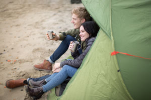Young couple camping on the beach in fall