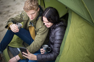 Young couple using a smartphone on a camping trip