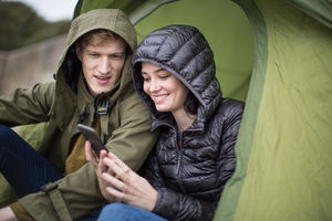 Young couple using a smartphone on a camping trip