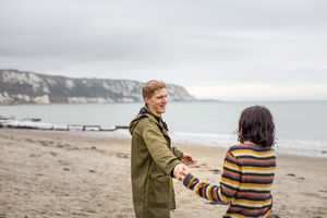 Couple holding hands on a winter beach break