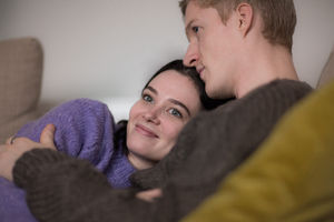 Couple at home cuddling on sofa