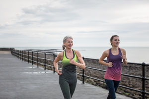 Active senior woman running with daughter 
