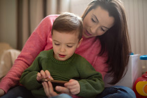 Preschool boy playing with smartphone with Mother