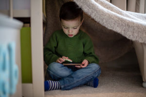 Preschool boy playing with smartphone in den
