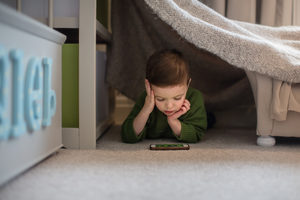 Preschool boy playing with smartphone in den