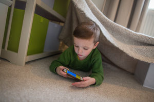 Preschool boy playing with smartphone in den