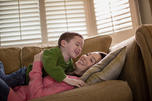 Mother tickling Son on sofa