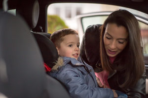 Mother putting Son in car seat safely