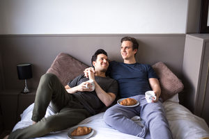 Young male couple relaxing with breakfast in bed