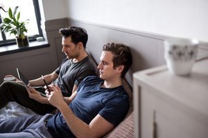 Young male couple using smartphone and digital tablet