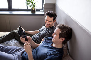 Young male couple using smartphone and digital tablet