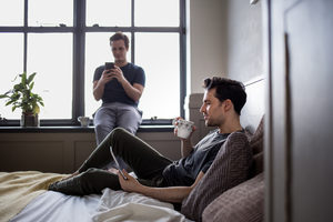 Young male couple on personal devices