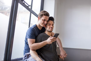 Young male couple looking at smartphone together