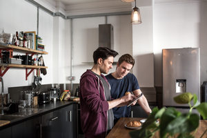 Young male couple looking at digital tablet in kitchen
