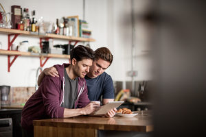 Young male couple looking at digital tablet in kitchen
