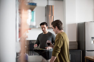 Young male couple cooking in kitchen