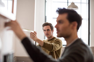 Young male couple measuring wall