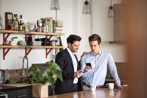 Young male couple in kitchen having breakfast before work