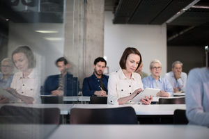 Mature student taking notes on digital tablet in a lecture