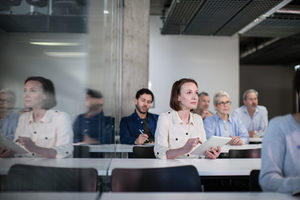 Mature student taking notes on digital tablet in a lecture