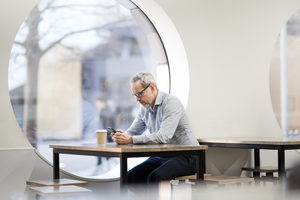 Businessman waiting in cafe checking smartphone