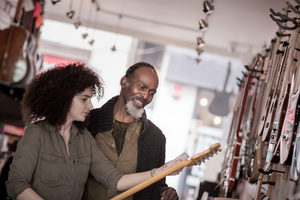 Small business owner helping customer in a guitar store